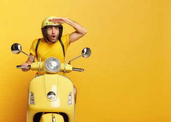 stupefied guy with helmet driving yellow scooter